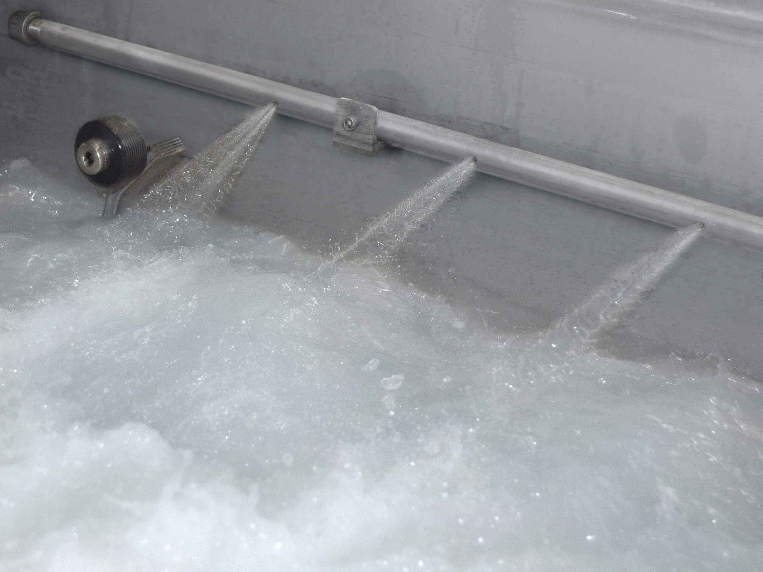 Spray bar sprays water out at a high pressure inside an aqueous parts washer.