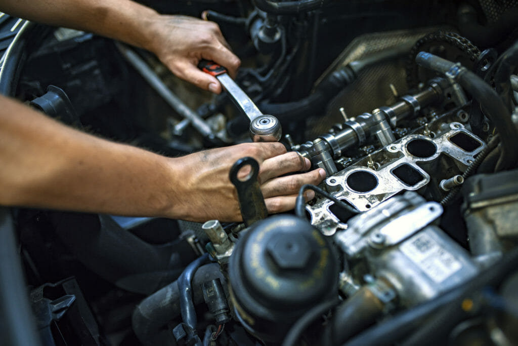 A mechanic uses a ratchet wrench to work on an automotive engine.