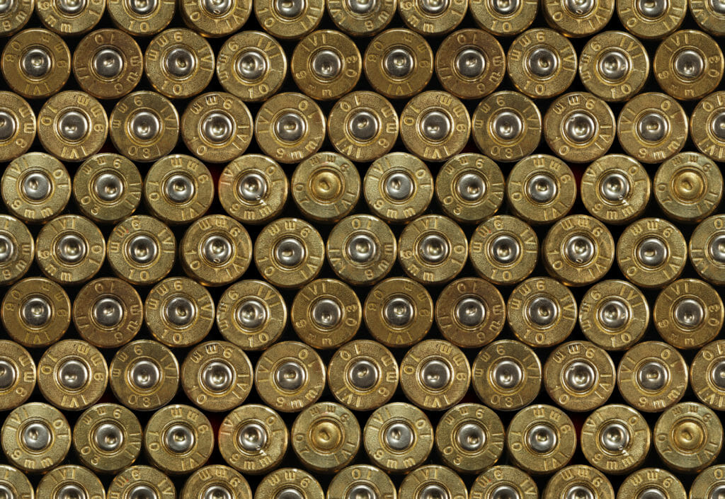Numerous brass shell casings are lined up against one another, filling the frame.