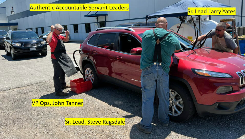 Servant leaders on the Jenfab team fuel up a red SUV with gas and clean the windshield.
