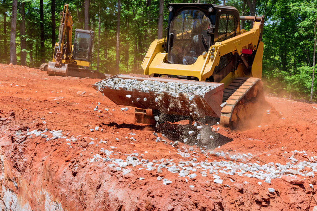 An excavator hauls gravel across a construction site.